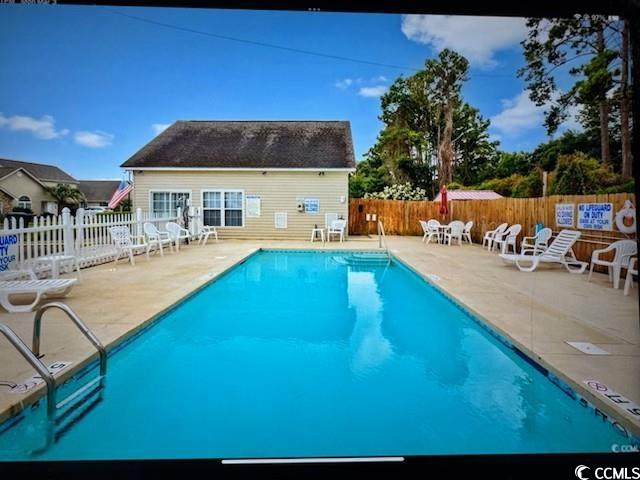 pool with a patio area and fence