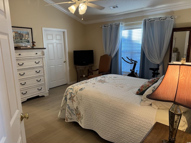 bedroom featuring crown molding, ceiling fan, vaulted ceiling, visible vents, and wood finished floors