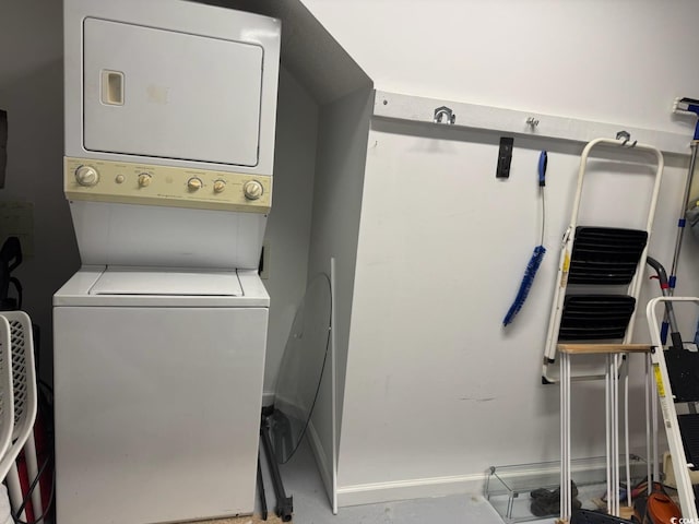 clothes washing area with baseboards, stacked washer / drying machine, and laundry area