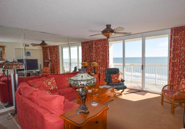 carpeted living room featuring expansive windows, a ceiling fan, visible vents, a water view, and a textured ceiling