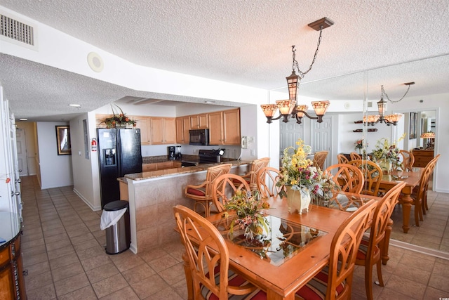 dining room with a notable chandelier, light tile patterned flooring, visible vents, and a textured ceiling