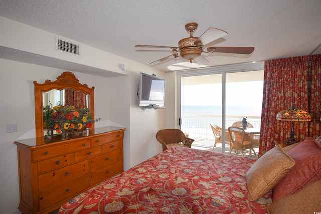 bedroom featuring visible vents, a ceiling fan, access to outside, a textured ceiling, and a wall of windows