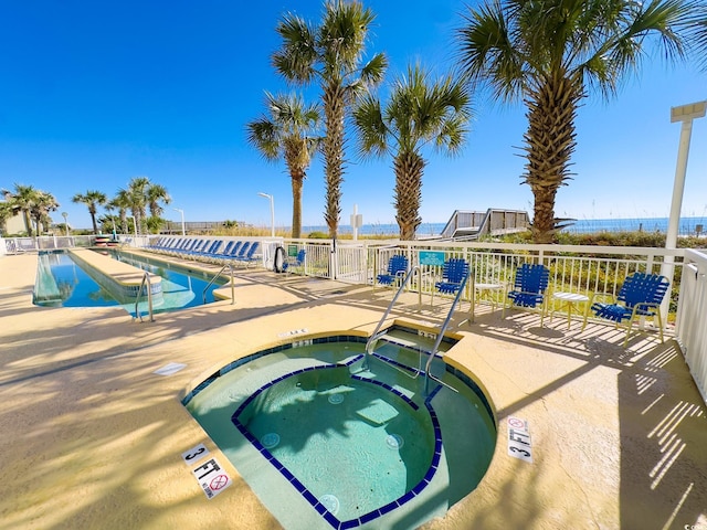 pool featuring a patio area, a community hot tub, and fence