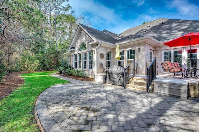 rear view of property with french doors, brick siding, a patio area, and a shingled roof