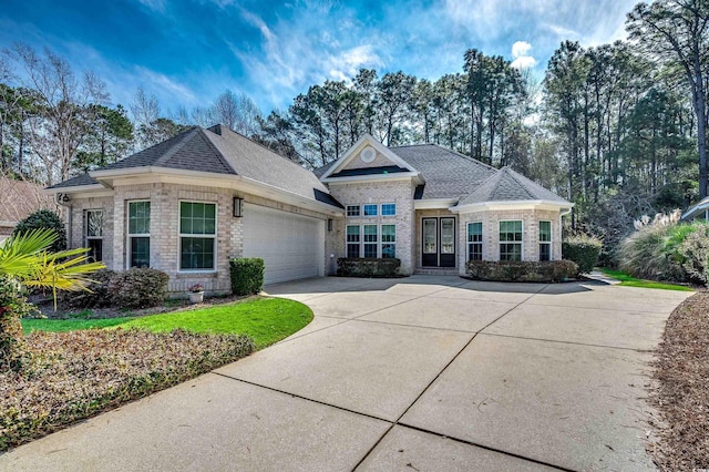 view of front of house with brick siding, driveway, an attached garage, and roof with shingles