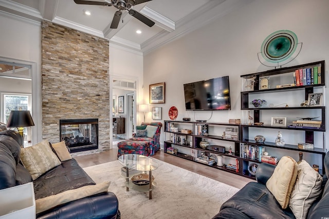 living room with coffered ceiling, wood finished floors, crown molding, a fireplace, and beam ceiling