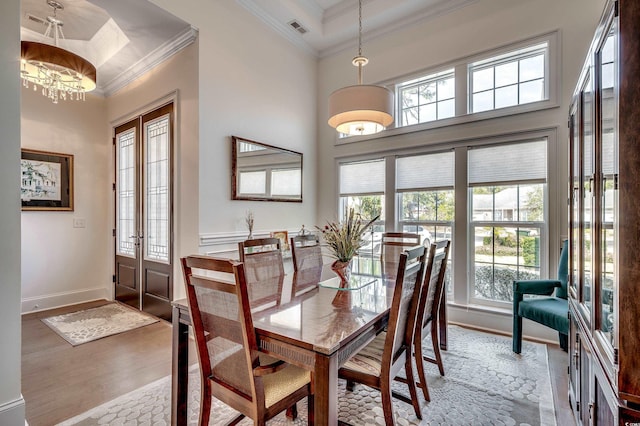 dining area featuring a towering ceiling, wood finished floors, visible vents, and crown molding