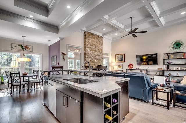 kitchen featuring a center island with sink, coffered ceiling, light wood-style flooring, open floor plan, and a sink