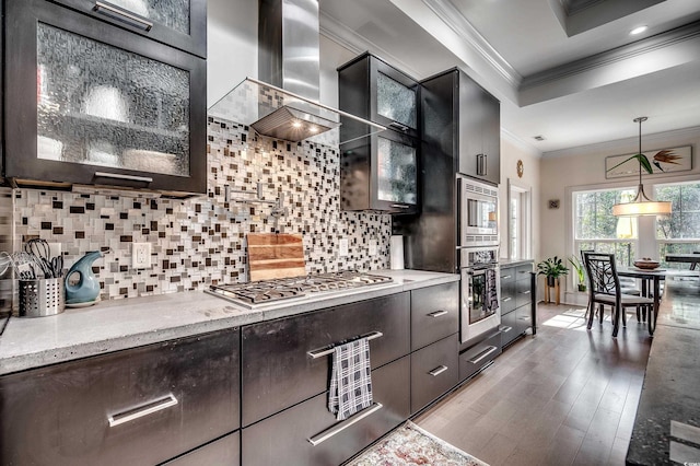 kitchen with stainless steel appliances, wood finished floors, wall chimney range hood, backsplash, and crown molding