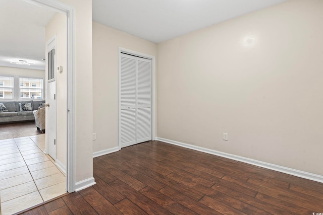 unfurnished bedroom featuring hardwood / wood-style flooring, baseboards, and a closet