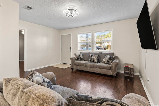 living room featuring baseboards, visible vents, a textured ceiling, and hardwood / wood-style floors