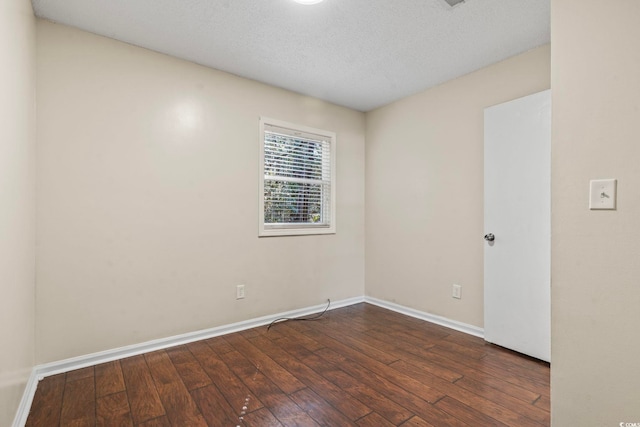 empty room with a textured ceiling, baseboards, and dark wood-style flooring