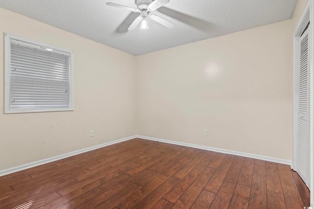 spare room featuring a textured ceiling, dark wood-style flooring, a ceiling fan, and baseboards