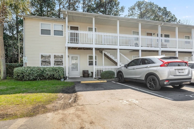 view of front of house with covered porch, uncovered parking, and a front lawn