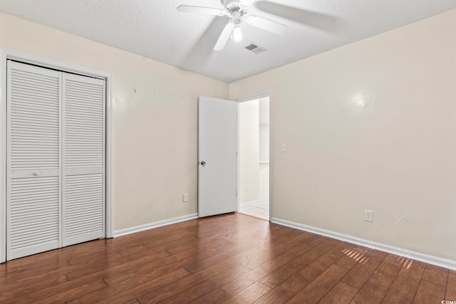 unfurnished bedroom featuring baseboards, visible vents, hardwood / wood-style floors, a textured ceiling, and a closet