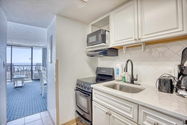 kitchen featuring black appliances, tasteful backsplash, a sink, and white cabinets