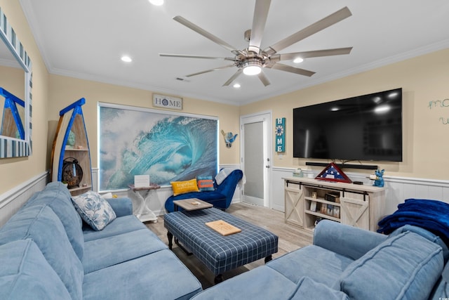 living room with ornamental molding, wainscoting, wood finished floors, and a ceiling fan