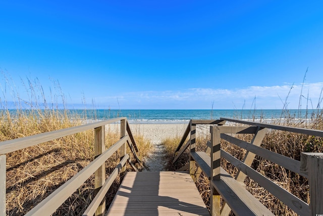 view of property's community with a water view and a beach view