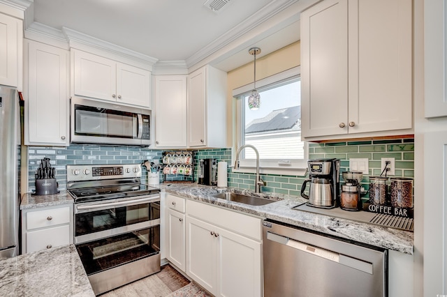 kitchen with visible vents, decorative backsplash, appliances with stainless steel finishes, white cabinetry, and a sink