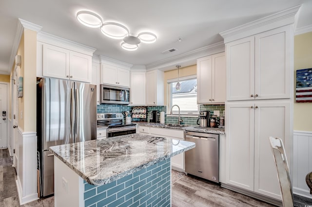 kitchen with light stone counters, stainless steel appliances, visible vents, white cabinetry, and a sink