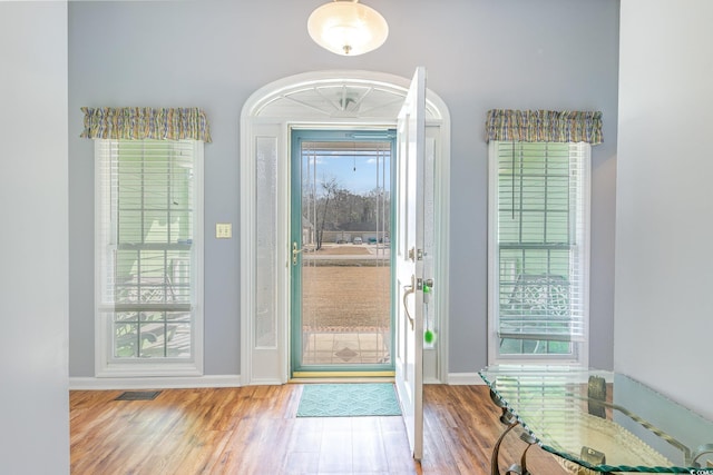 foyer entrance with visible vents, plenty of natural light, baseboards, and wood finished floors