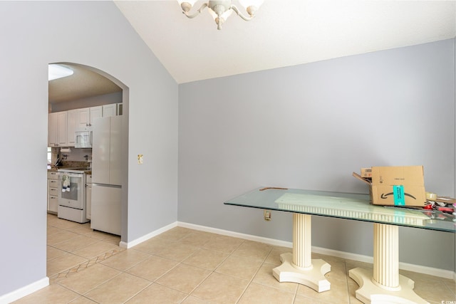 interior space with arched walkways, light tile patterned floors, lofted ceiling, and baseboards