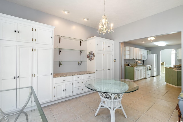 dining space with arched walkways, light tile patterned flooring, and a notable chandelier