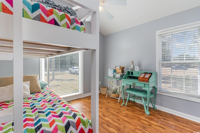 bedroom with lofted ceiling, multiple windows, baseboards, and wood finished floors