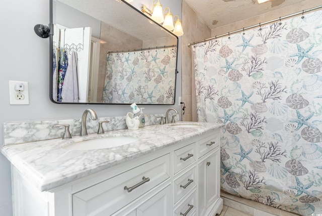 bathroom with tile patterned flooring, a sink, a textured ceiling, and double vanity