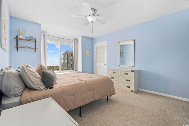 bedroom with a textured ceiling, ceiling fan, carpet flooring, baseboards, and a closet