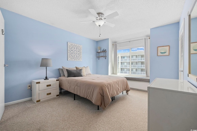 bedroom with light carpet, ceiling fan, a textured ceiling, and baseboards