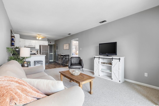 living room with light carpet, baseboards, visible vents, and a ceiling fan