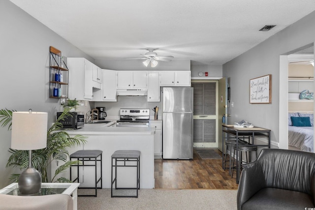 kitchen with ceiling fan, under cabinet range hood, stainless steel appliances, a peninsula, and light countertops