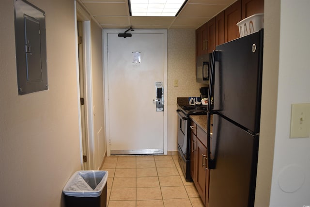 kitchen with light tile patterned floors, a paneled ceiling, dark countertops, electric panel, and black appliances