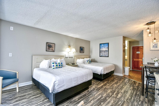 bedroom featuring a textured ceiling, baseboards, and wood finished floors