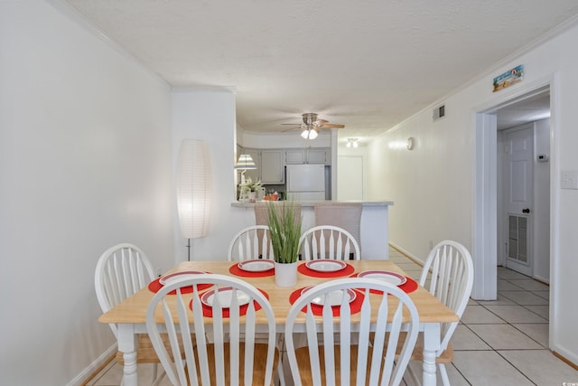 dining room with a ceiling fan, visible vents, crown molding, and light tile patterned floors