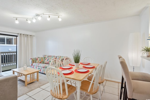 dining space featuring a textured ceiling, light tile patterned floors, and baseboards