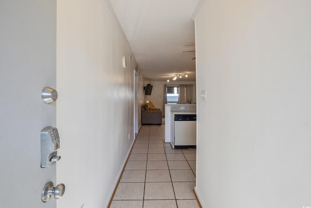 hallway featuring light tile patterned floors, baseboards, and rail lighting