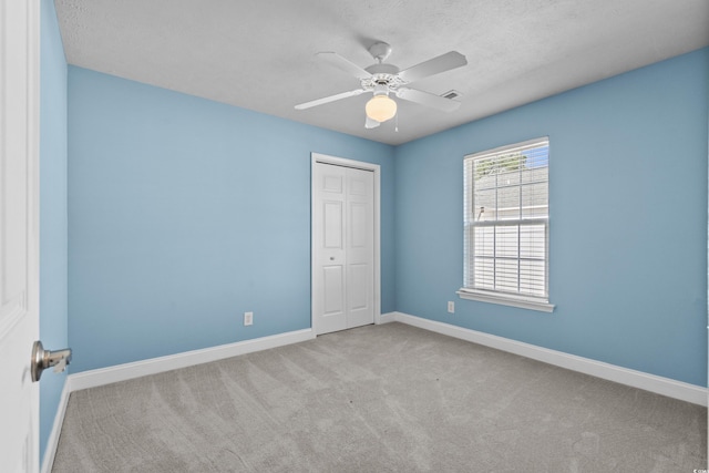 unfurnished bedroom featuring visible vents, baseboards, carpet floors, a closet, and a ceiling fan