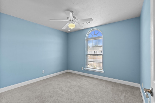 carpeted empty room with a ceiling fan, baseboards, and visible vents