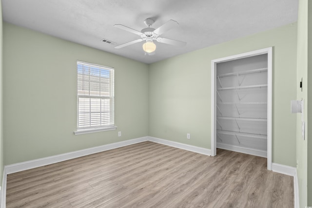 unfurnished bedroom featuring a closet, visible vents, baseboards, and wood finished floors