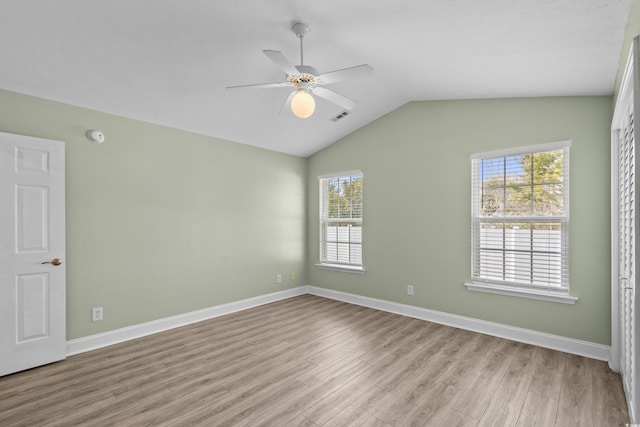 spare room with light wood-type flooring, visible vents, baseboards, ceiling fan, and vaulted ceiling