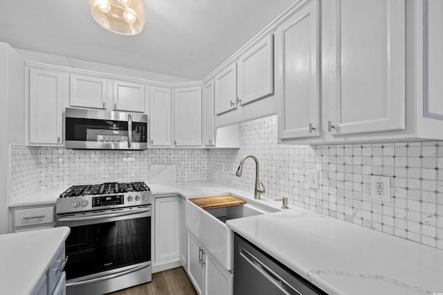 kitchen with tasteful backsplash, white cabinets, and appliances with stainless steel finishes