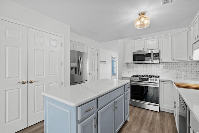 kitchen with decorative backsplash, appliances with stainless steel finishes, wood finished floors, and light countertops