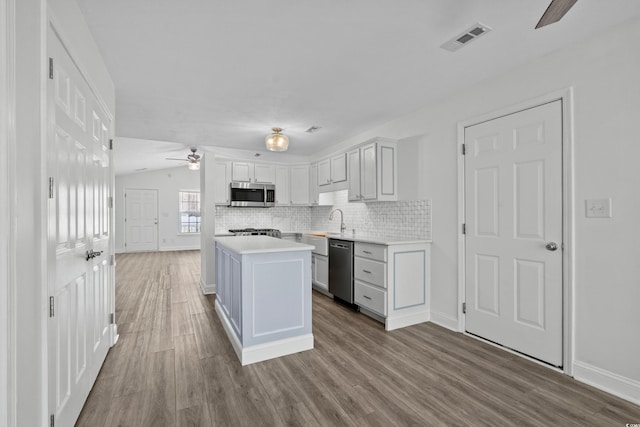 kitchen featuring wood finished floors, visible vents, light countertops, appliances with stainless steel finishes, and tasteful backsplash