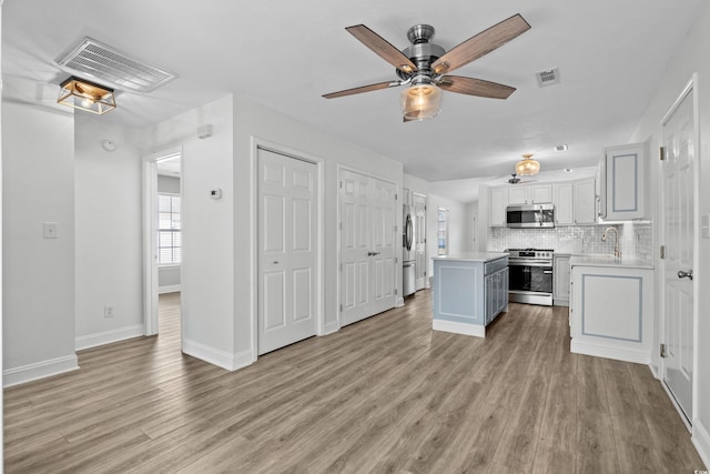 kitchen with a sink, stainless steel appliances, a kitchen island, and visible vents