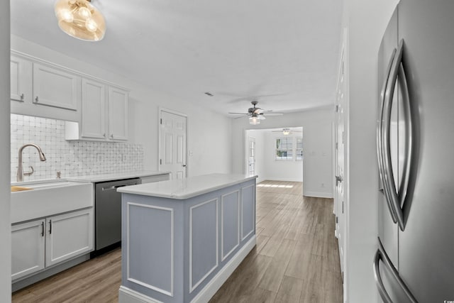 kitchen with tasteful backsplash, a center island, stainless steel appliances, light wood-style floors, and white cabinets