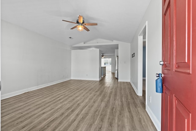 interior space with baseboards, light wood-style floors, a ceiling fan, and vaulted ceiling