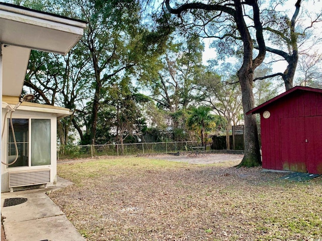 view of yard with a storage shed, an outdoor structure, fence, and a sunroom