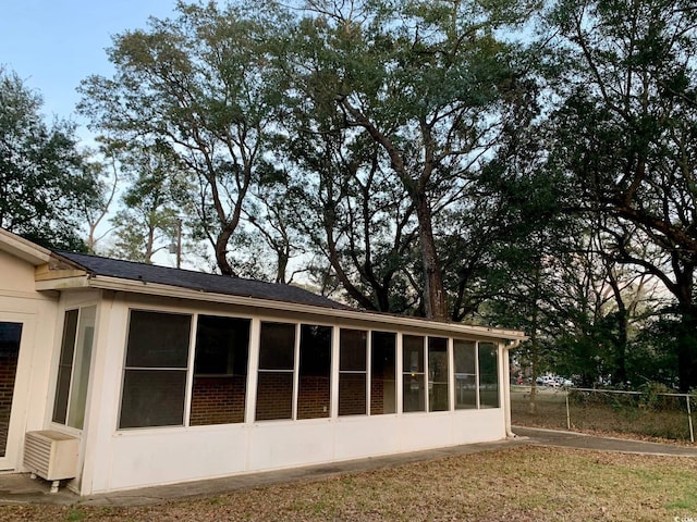 view of side of property with fence and a sunroom